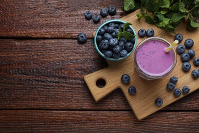 Glass of blueberry smoothie with mint and fresh berries on wooden table, flat lay. Space for text