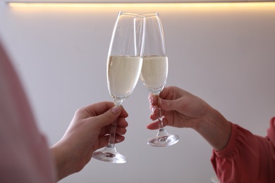 Photo of Women clinking glasses of champagne indoors, closeup. Holiday cheer and drink