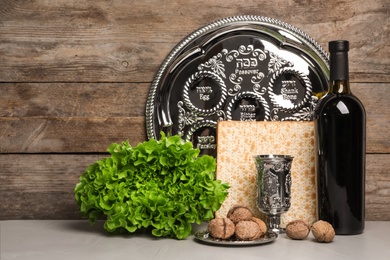 Symbolic Passover (Pesach) items on table against wooden background, space for text