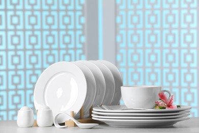 Photo of Set of clean dishware with flowers on light grey table