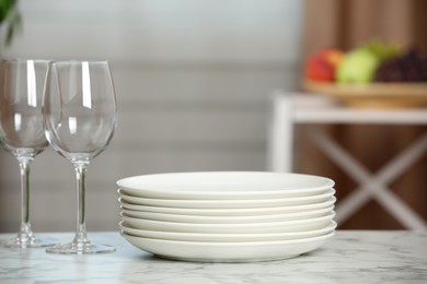 Stack of plates and glasses on white marble table indoors