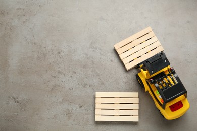 Toy forklift and wooden pallets on light grey table, flat lay. Space for text