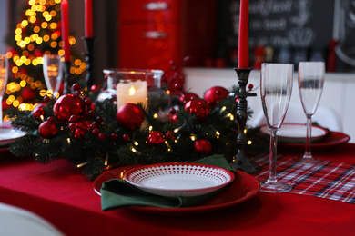 Table served for festive dinner and blurred Christmas tree in stylish kitchen interior, closeup