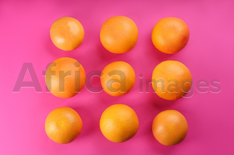 Tasty ripe grapefruits on magenta background, flat lay