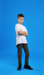 Full length portrait of preteen boy on light blue background