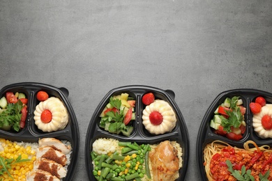 Top view of lunchboxes with different meals on grey table, space for text. Healthy food delivery