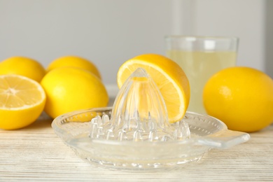 Plastic juicer with half of lemon on white wooden table
