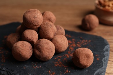 Tasty chocolate truffles powdered with cacao on slate board, closeup