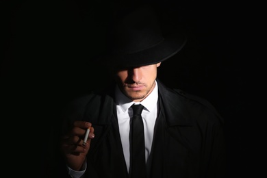 Old fashioned detective with cigarette on dark background