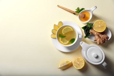 Photo of Delicious ginger tea and ingredients on beige background, flat lay. Space for text