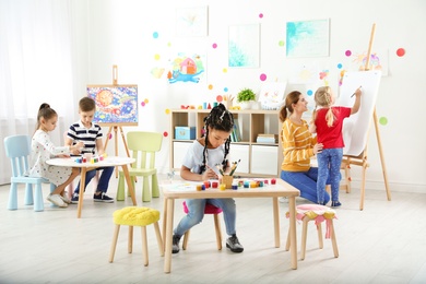 Children with female teacher at painting lesson indoors