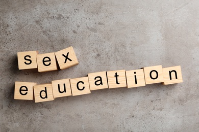 Wooden blocks with phrase "SEX EDUCATION" on stone background, flat lay
