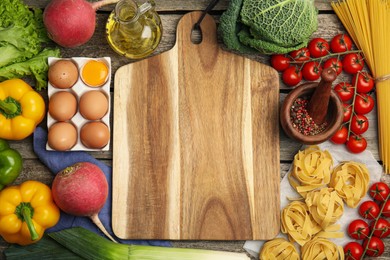 Board surrounded by different ingredients on wooden table, flat lay with space for text. Cooking classes