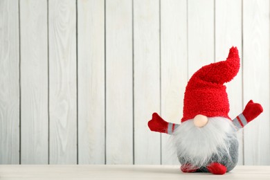 Cute Christmas gnome on table against white wooden background. Space for text