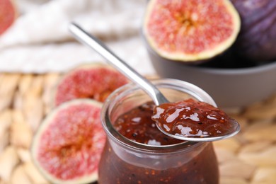 Photo of Tasty sweet fig jam with spoon and fruits on table, closeup