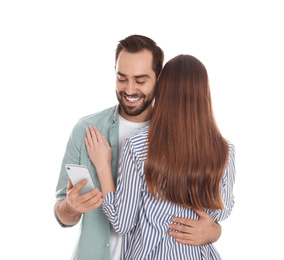 Man interested in smartphone while hugging his girlfriend on white background. Relationship problems