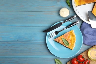 Piece of delicious pie with minced meat and basil served on light blue wooden table, flat lay. Space for text