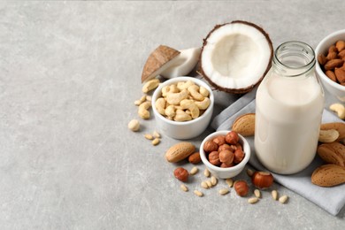Vegan milk and different nuts on light table. Space for text