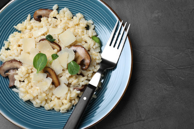 Photo of Delicious risotto with cheese and mushrooms on dark grey table, top view