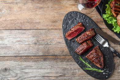 Delicious sliced beef tenderloin served on wooden table, flat lay. Space for text