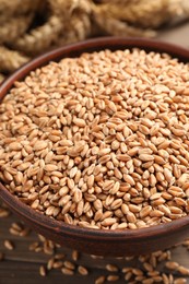 Photo of Wheat grains in bowl on wooden table, closeup