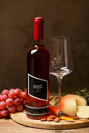 Photo of Bottle of red wine with glass and appetizers on wooden table