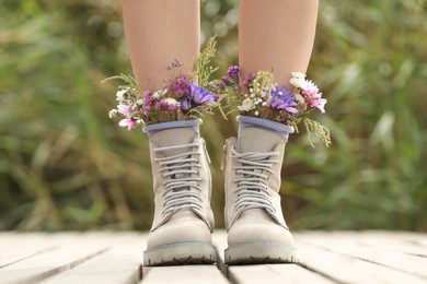 Woman standing on wooden pier with flowers in socks outdoors, closeup