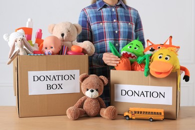 Little boy near donation boxes with toys against light background, closeup