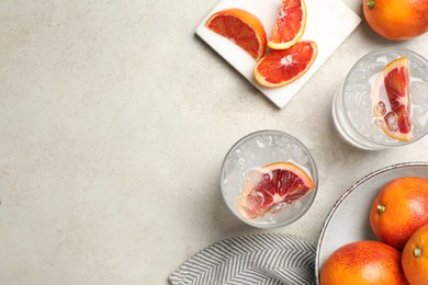 Delicious refreshing drink with sicilian orange and ice cubes served on light table, flat lay. Space for text