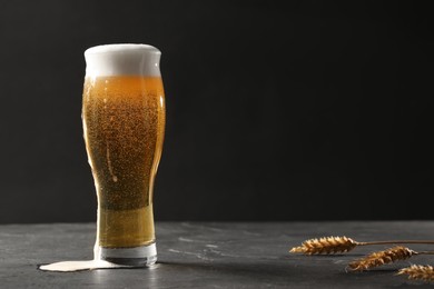 Glass of beer and spikes on black table. Space for text