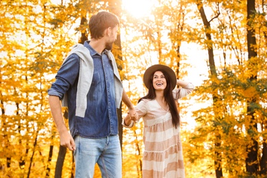 Happy couple walking in sunny autumn park