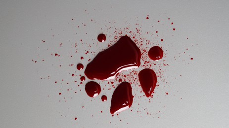Stain and splashes of blood on grey background, top view