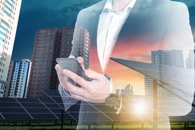 Double exposure of businessman with smartphone and solar panels installed outdoors. Alternative energy source