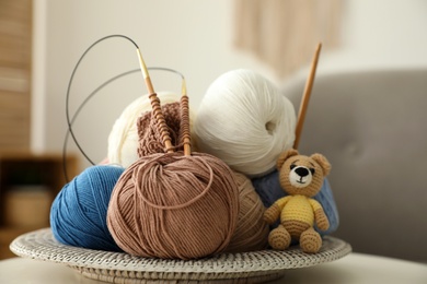 Photo of Toy bear, clews with needles and crochet on table. Engaging in hobby