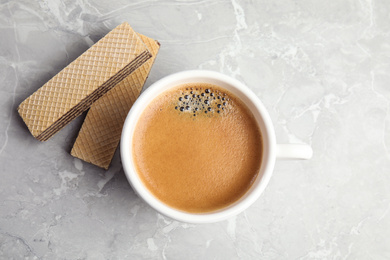 Delicious wafers and cup of coffee for breakfast on grey marble table, flat lay