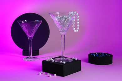 Photo of Beautiful composition with martini glasses and pearls on pink background