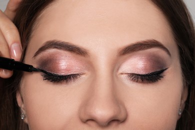 Photo of Artist applying black eyeliner onto woman's face, closeup