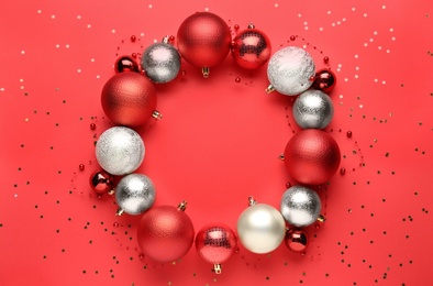 Beautiful festive wreath made of color Christmas balls on red background, top view