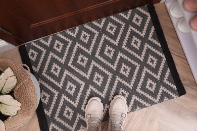 Stylish door mat with shoes on floor indoors, flat lay