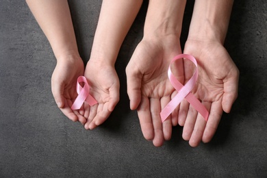 Woman and girl holding pink ribbons on grey background, top view. Breast cancer awareness