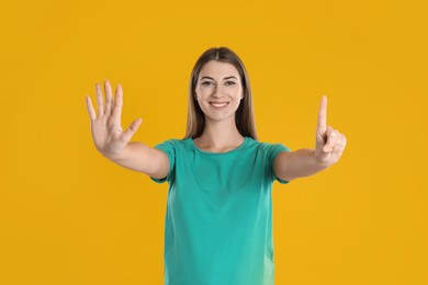 Woman showing number six with her hands on yellow background