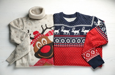 Photo of Warm Christmas sweaters on white wooden table, top view