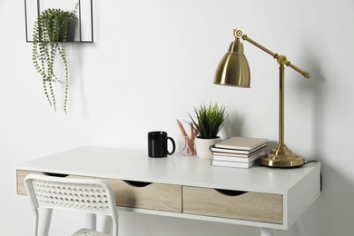 Photo of Comfortable workplace with white desk near wall