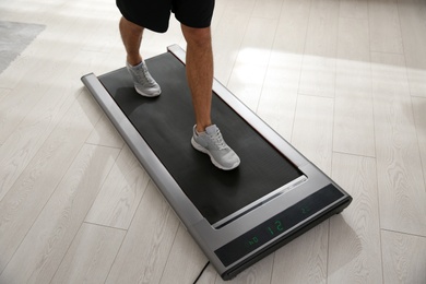 Sporty man training on walking treadmill at home, closeup