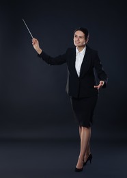 Happy young conductor with baton on dark background