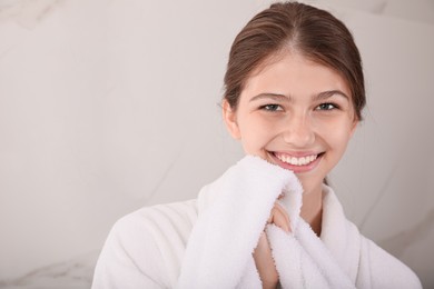 Beautiful teenage girl wiping face with towel at home, space for text