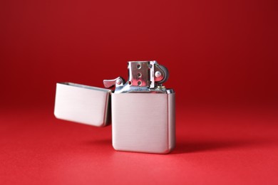 Photo of Gray metallic cigarette lighter on red background, closeup