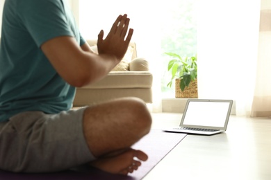 Man practicing yoga while watching online class at home during coronavirus pandemic, closeup. Social distancing