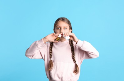 Sick little girl using nasal sprays on light blue background