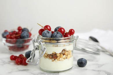 Delicious yogurt parfait with fresh berries on white marble table, closeup